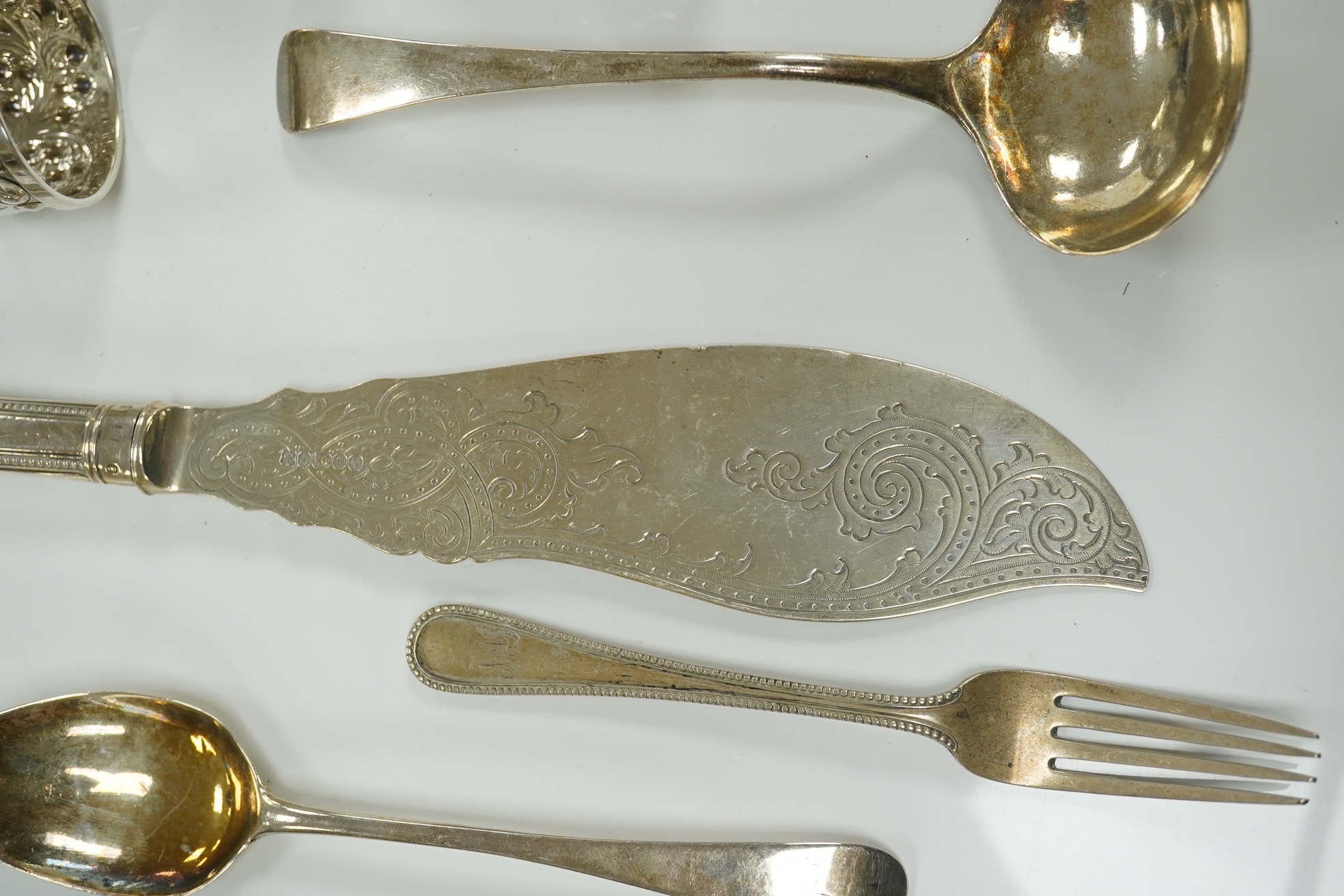 Small silver including a pair of napkin rings and two others, a Georgian sauce ladle and two similar dessert spoons, a fish slice, fork and an unmarked toddy ladle with inset coin bowl. Condition - poor to fair